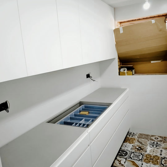 Cocina blanca sin tiradores con cajón organizador, encimera gris y suelo de baldosas hidráulicas