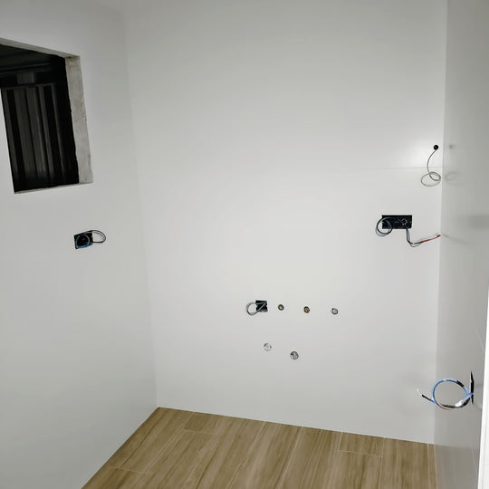 Espacio vacío antes de instalar una cocina blanca en U, con suelo efecto madera y conexiones preparadas
