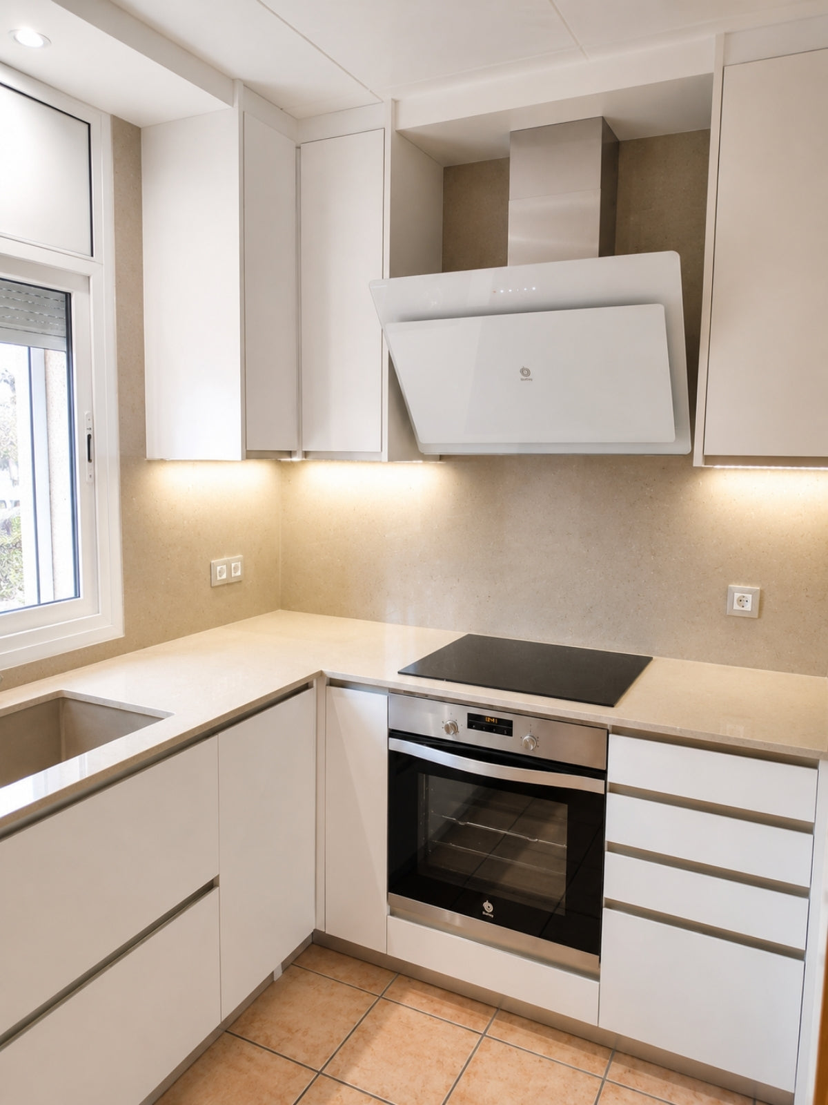 Cocina blanca en L a medida con campana inclinada y horno integrado en Badalona