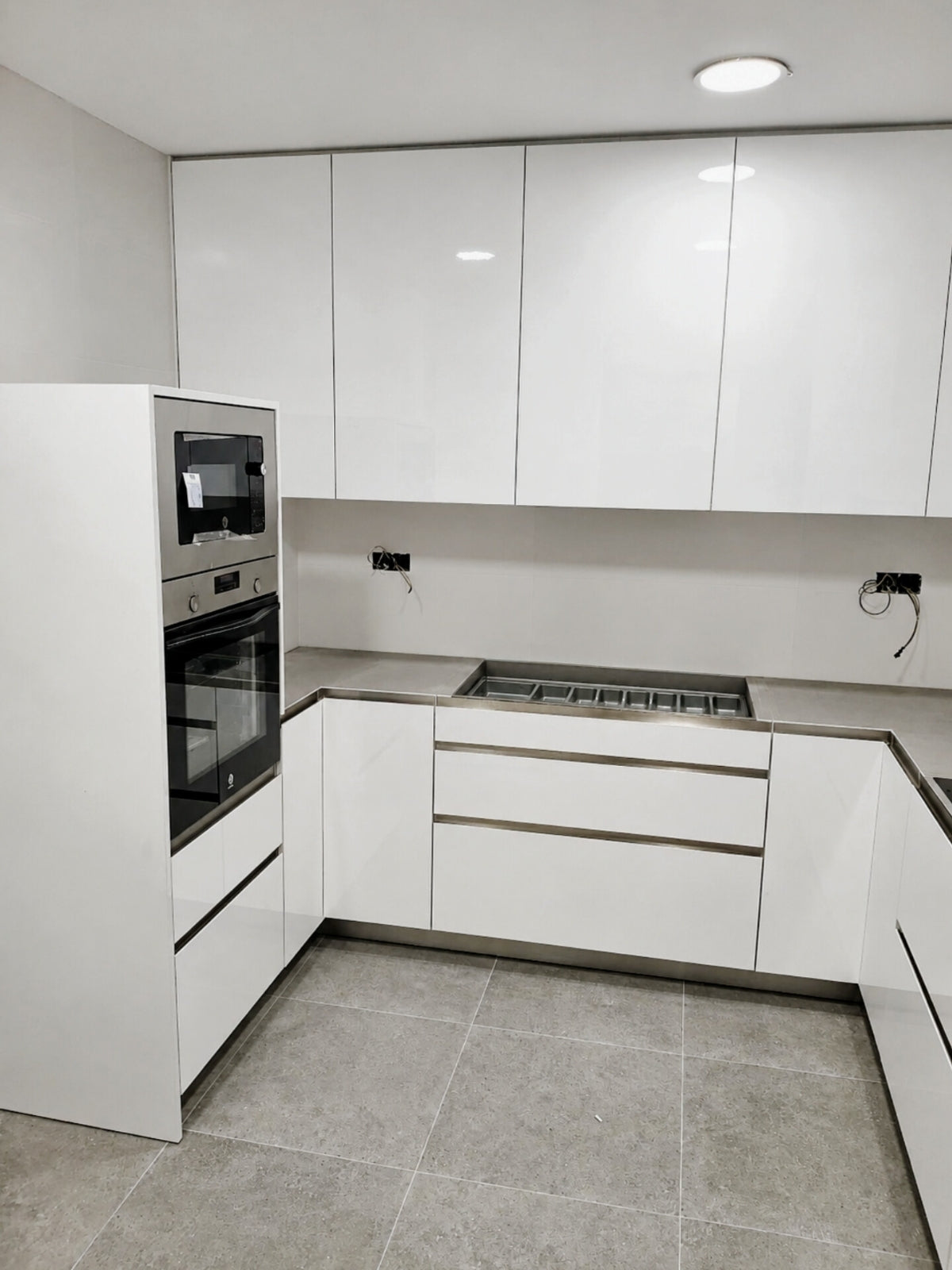 Cocina blanca en U a medida con torre de horno y muebles altos en Tiana