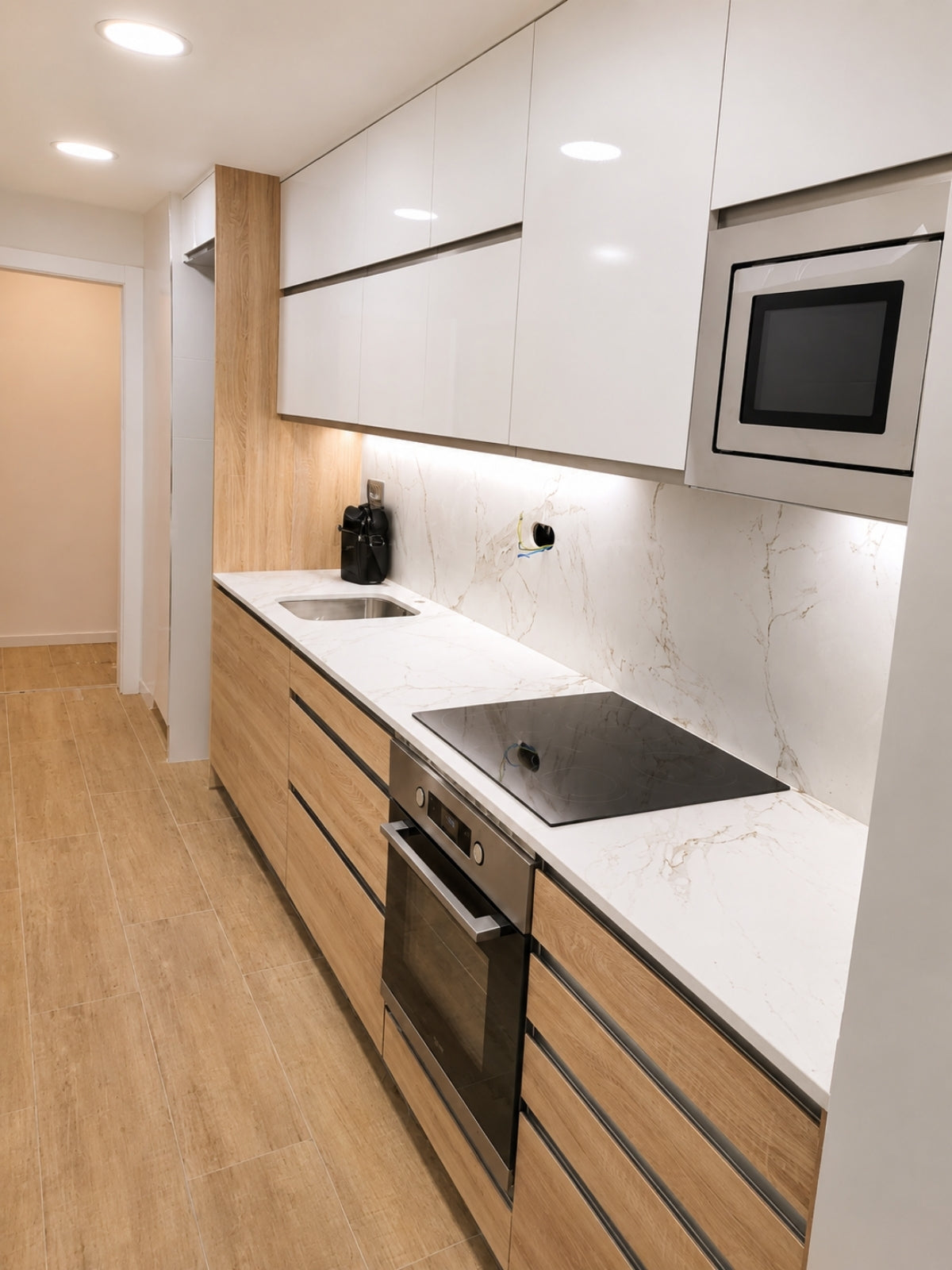 Cocina blanca y madera lineal a medida con microondas integrado en Vilassar de Mar