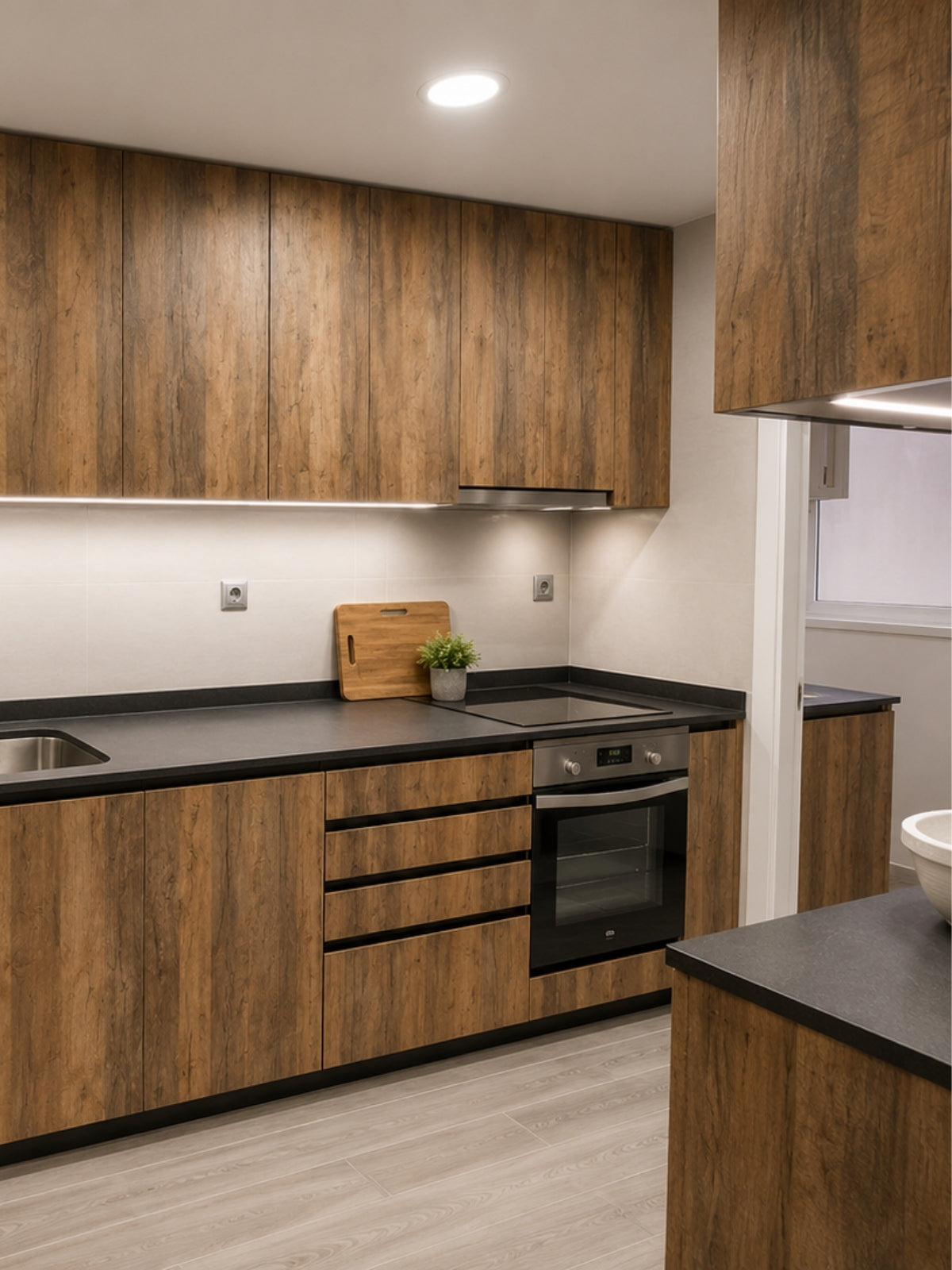 Cocina de madera en L a medida con campana de acero y encimera oscura en Tiana