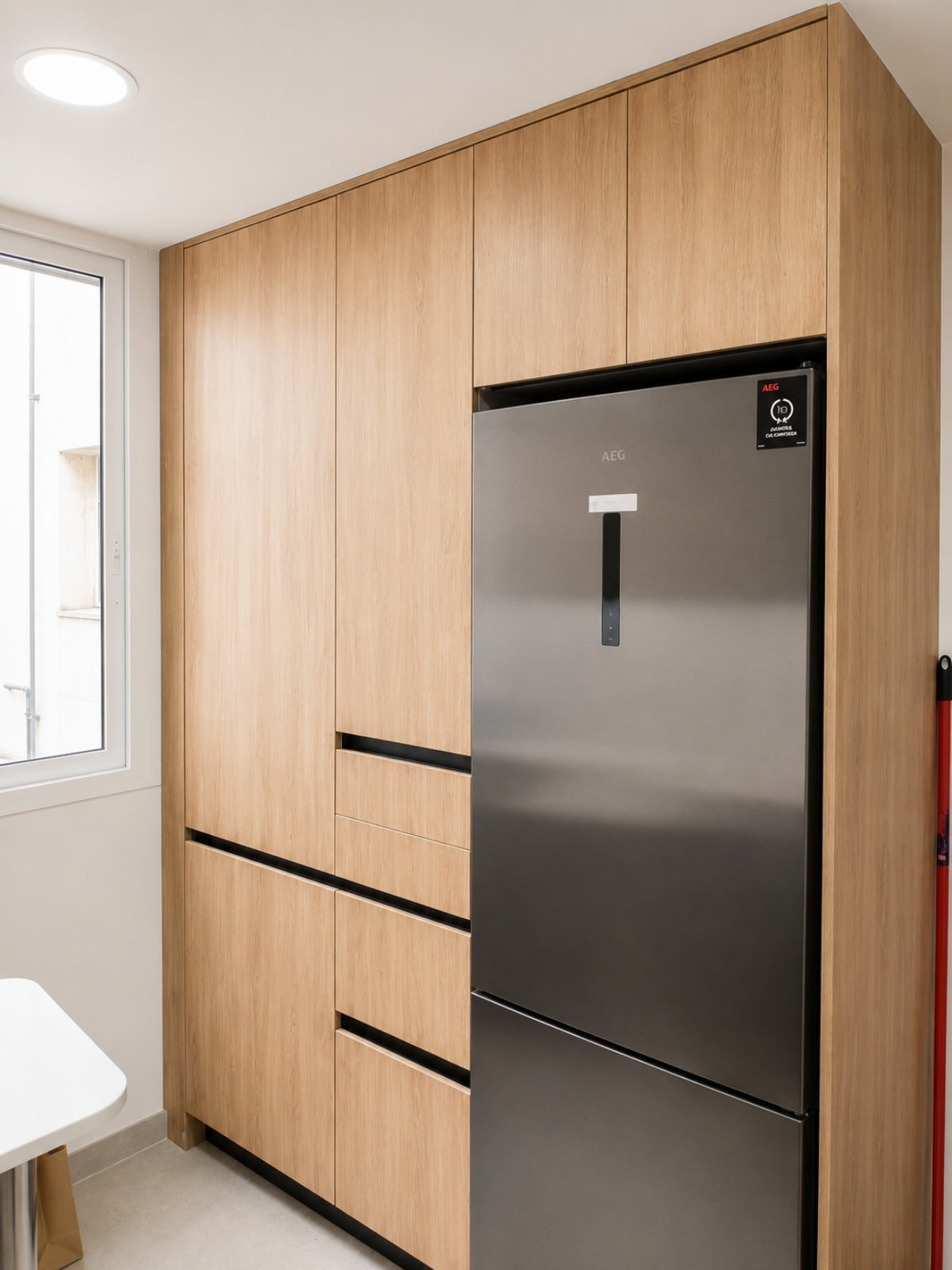 Cocina a medida en madera con columna para frigorífico en Sabadell