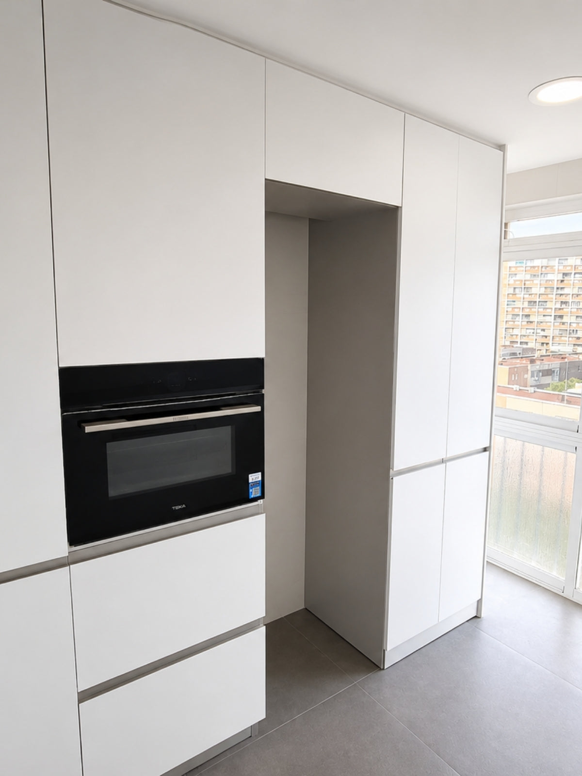 Columna de cocina blanca a medida con horno integrado y hueco para frigorífico en El Masnou