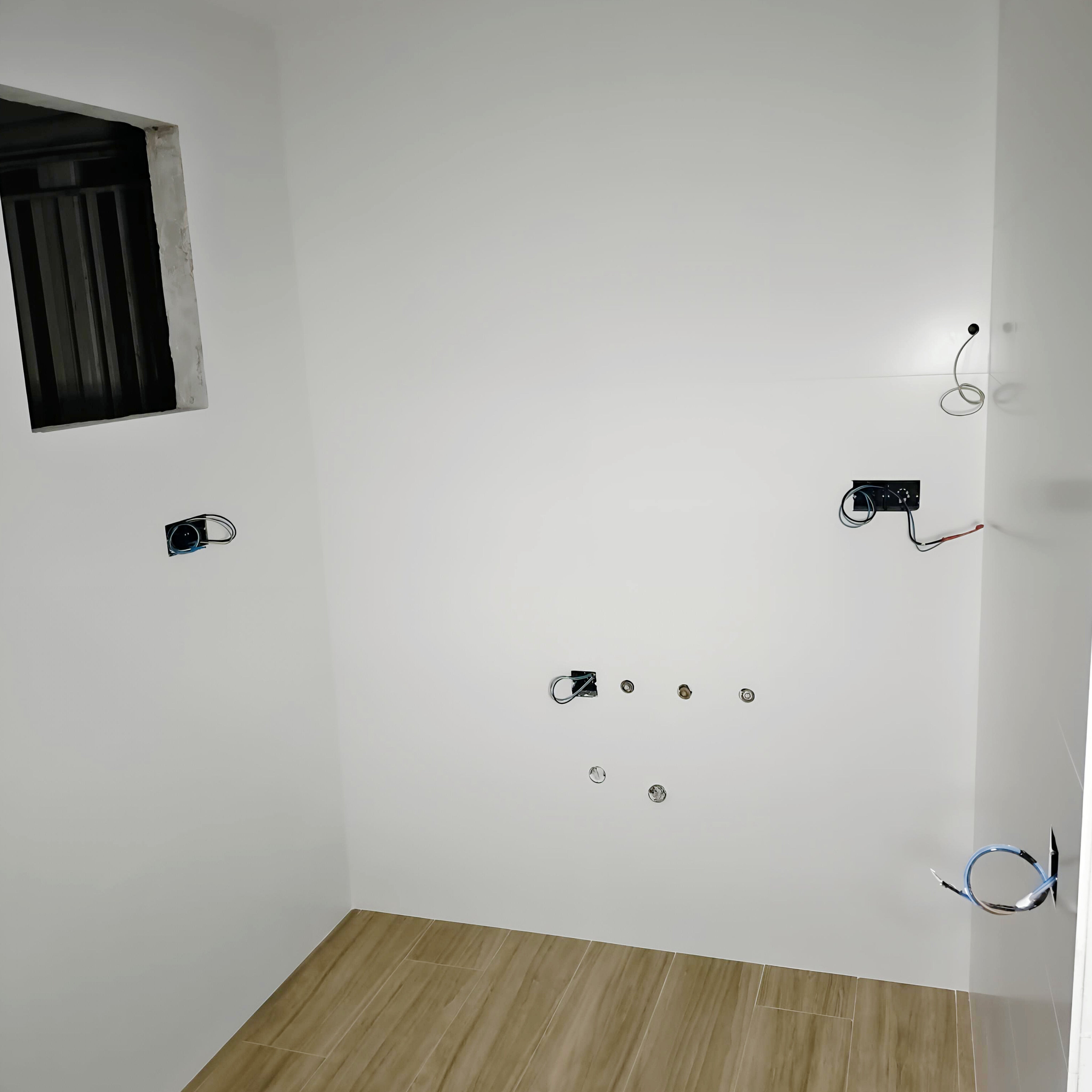Espacio vacío antes de instalar una cocina blanca en U, con suelo efecto madera y conexiones preparadas